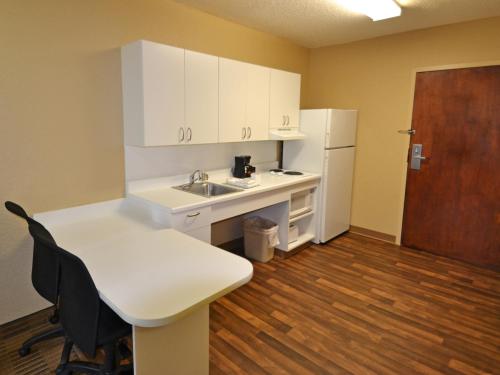a kitchen with white cabinets and a sink and a table at Extended Stay America Suites - Boise - Airport in Boise