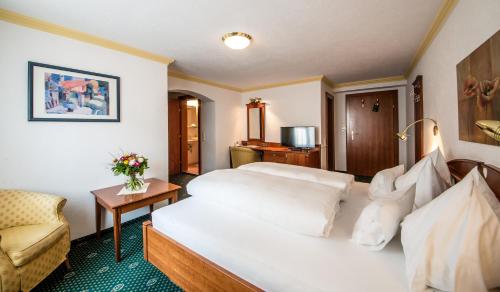 a hotel room with a bed and a chair at Hotel Kristall in Sankt Anton am Arlberg