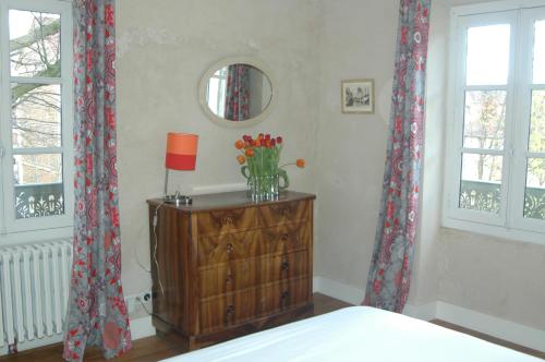 a bedroom with a dresser with a lamp and flowers on it at Le Clos de l'Abbaye in Cluny