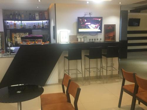 a bar with stools and a tv in a room at Sunrise Hotel Cameria in Durrës