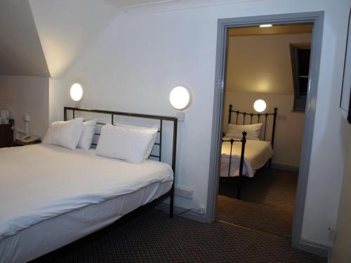 a bedroom with a bed with white pillows and a mirror at 247Hotel in Oldham