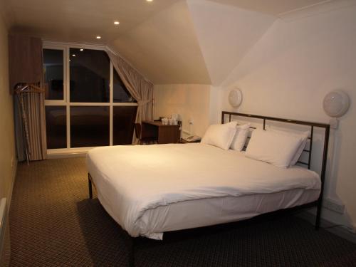 a bedroom with a large white bed with a window at 247Hotel in Oldham