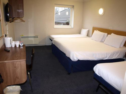 a hotel room with two beds and a desk at 247Hotel in Oldham