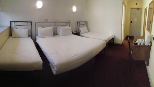 two beds in a room with white sheets and pillows at 247Hotel in Oldham