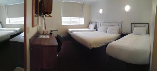 a hotel room with two beds and a desk at 247Hotel in Oldham