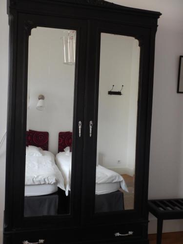 a black cabinet with two mirrors next to a bed at Le Clos de l'Abbaye in Cluny