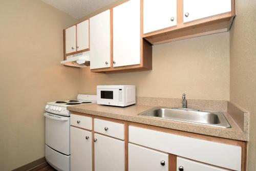 a small kitchen with a sink and a microwave at Suburban Studios Houston North I-45 in Houston