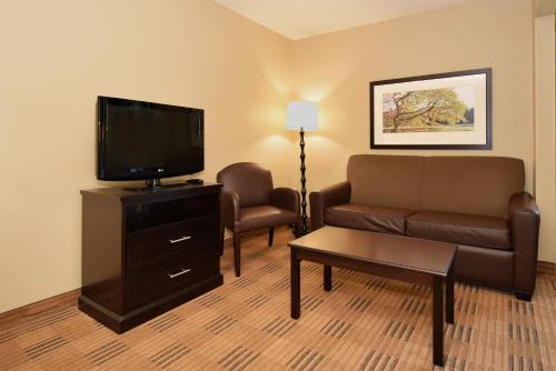 a living room with a couch and a flat screen tv at Suburban Studios Houston North I-45 in Houston
