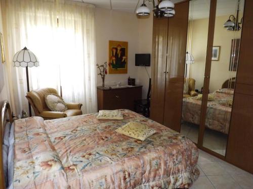 a bedroom with a bed and a chair and a mirror at B&B Le Grazie in Siniscola