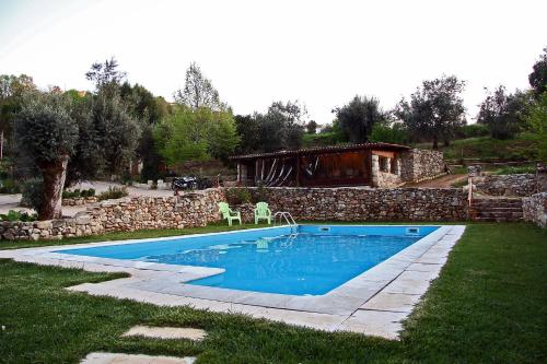 a swimming pool in a yard with a stone wall at Sete Quintas in Miranda do Corvo