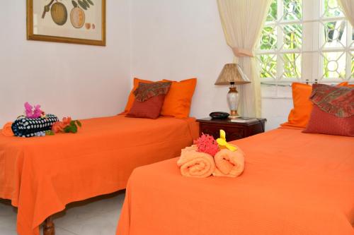 Habitación con 2 camas con sábanas de color naranja en Paradise Palms Jamaica Vacation Rental, en Montego Bay