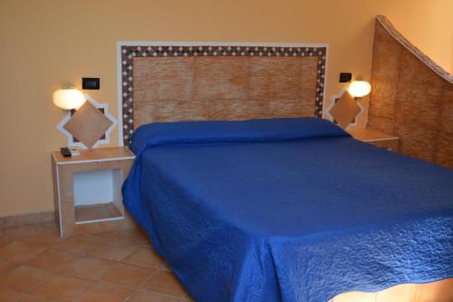 um quarto com uma cama azul e uma grande cabeceira de cama. em Hotel Mare Blu em Lampedusa