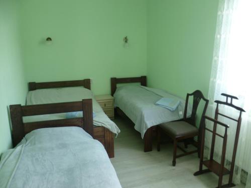 a room with two beds and a chair in it at Home Hotel in Kamianets-Podilskyi