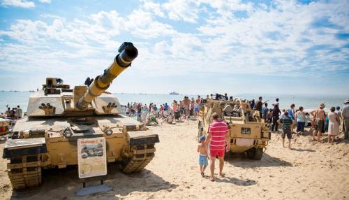 a group of people standing next to tanks on a beach at Hartford Court in Bournemouth