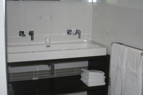 a bathroom with a white sink and towels at Grenshotel de Jonckheer in Ossendrecht