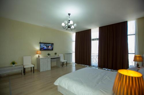 a bedroom with a white bed and a desk and windows at Ire Palace in Batumi