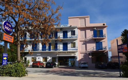 a pink building with cars parked in front of it at Hotel Solon in Tolo