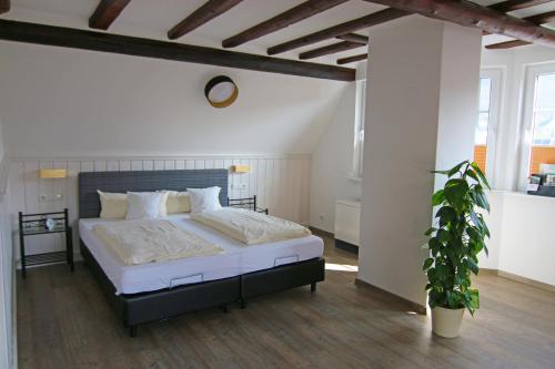 エレンツ・ポルタースドルフにあるFerienweingut Villa Hausmannの大型ベッドと鉢植えの植物が備わるベッドルーム1室