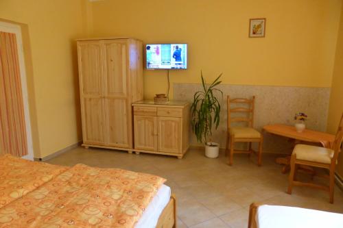 - une chambre avec un lit, une table et une télévision dans l'établissement Napfény Apartman és Vendégház, à Egerszalók