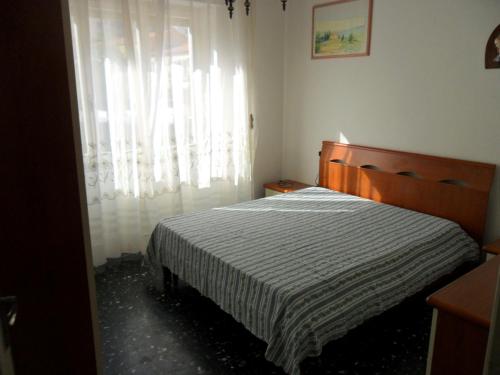 sypialnia z łóżkiem i oknem z zasłonami w obiekcie Parri Apartment w mieście Follonica