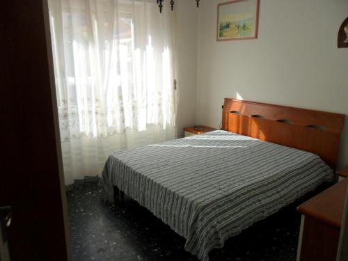 a bedroom with a bed and a window with curtains at Parri Apartment in Follonica