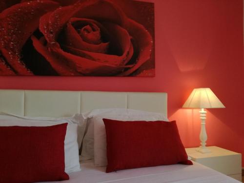 a bedroom with a red wall with a red rose above a bed at Casa del Corso in Taviano