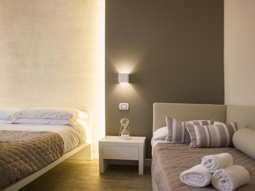 a bedroom with two beds and a night stand with towels at La Banchina Holiday Rooms in Trani