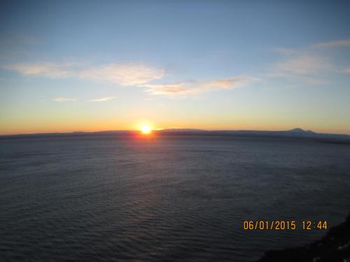 a sunset over the ocean with the sun in the sky at Smyrill Cottages in Þórshöfn