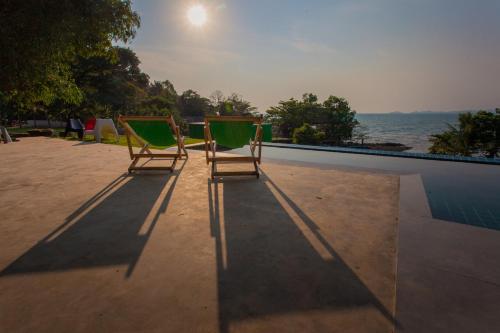two lawn chairs sitting next to a swimming pool at Bamboo Garden House in Laem Sing
