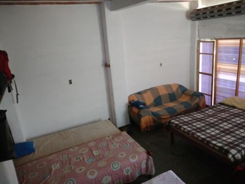 Pokój z 2 łóżkami, krzesłem i oknem w obiekcie Pouso e Camping do Miguel w mieście Aiuruoca