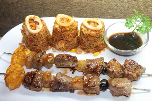 a plate of food with meat and onion rings and sauce at Deep Forest Garden Hotel in Puerto Princesa City