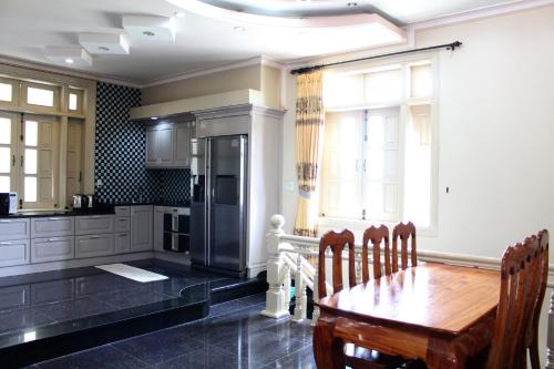 a kitchen with a wooden table and a refrigerator at Hoang Gia Doc Let in Doc Let