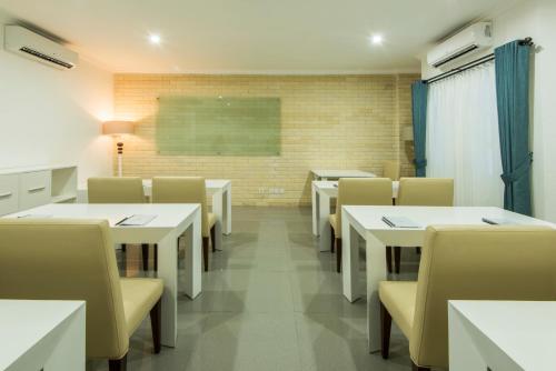 a classroom with white tables and chairs and a chalkboard at Yan's House Hotel in Kuta