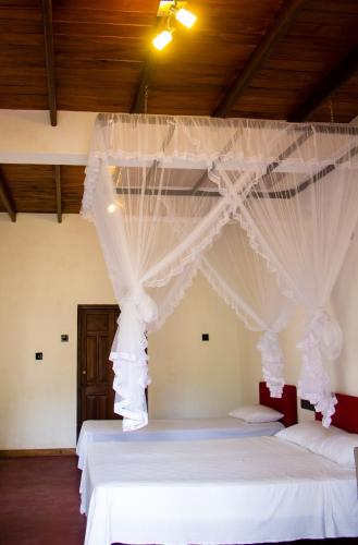 a bedroom with two beds with white drapes at Hotel La Felicita in Mirissa