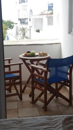 a table with two chairs and a plate of fruit on it at Very-Kokkos Pension 2 in Naxos Chora