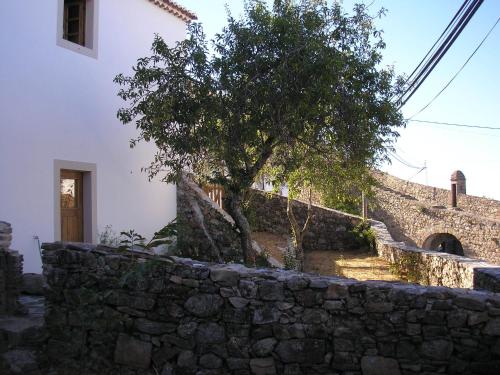 a stone wall with a tree in front of a building at Casa da Silveirinha in Marvão