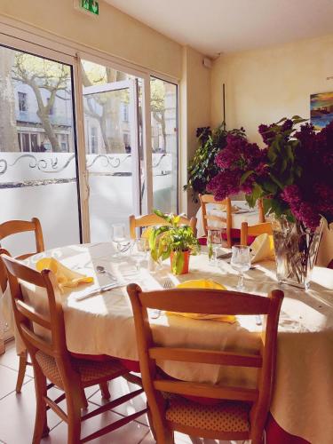 - une salle à manger avec une table, des chaises et des fleurs dans l'établissement Logis Hotels - Hôtel et Restaurant de la Montagne Noire, à Dourgne
