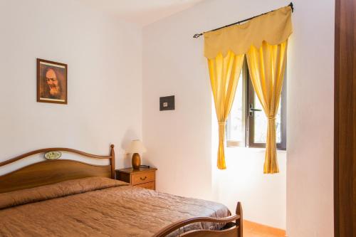 Tenuta Padre Pio في فييستي: غرفة نوم بسرير ونافذة ذات ستائر صفراء