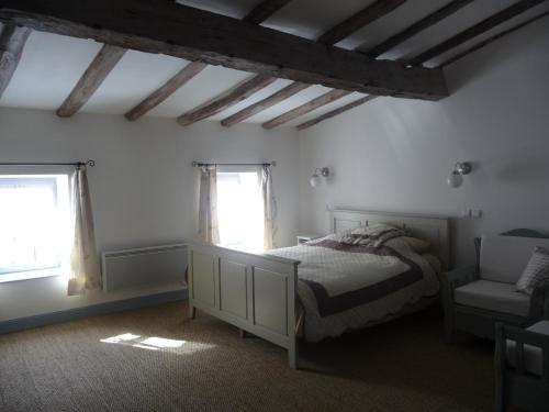 una camera con un letto e una sedia e due finestre di Les quatre provinces d'Irlande a Saint-Amant-Tallende