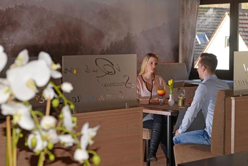 a man and woman sitting at a table in a restaurant at Hotel Die Kleine Blume in Erfweiler