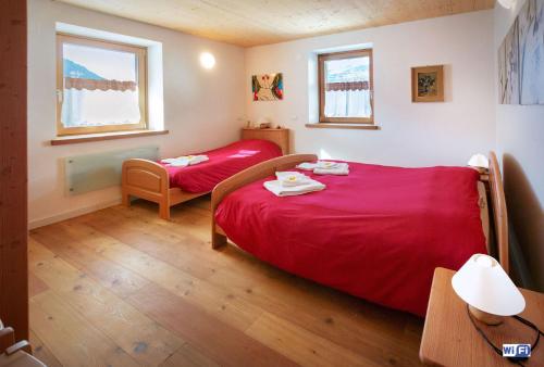 a small bedroom with a red bed and a chair at La Marmote Albergo Diffuso di Paluzza Testeons in Paluzza