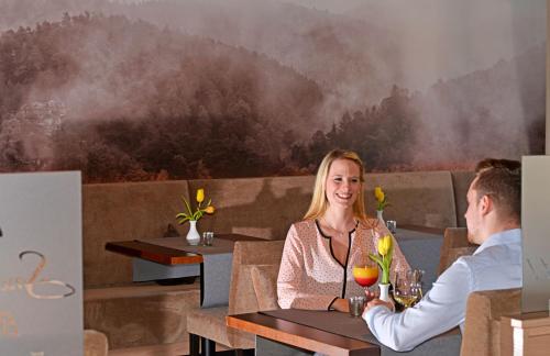 a man and woman sitting at a table in a restaurant at Hotel Die Kleine Blume in Erfweiler
