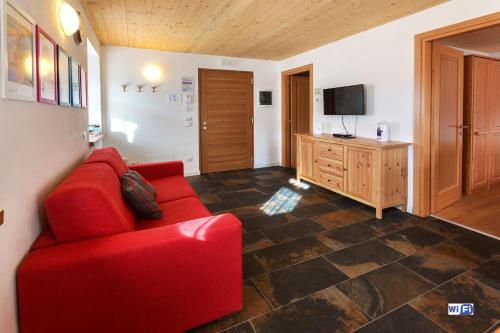 sala de estar con sofá rojo y TV en La Marmote Albergo Diffuso di Paluzza Testeons, en Paluzza
