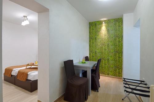 a bedroom with a table and a green wall at Hotel Fontana in Novi Sad