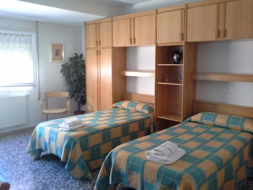 een kamer met 2 bedden en kasten met handdoeken erop bij Pensión Lacasta in Zaragoza