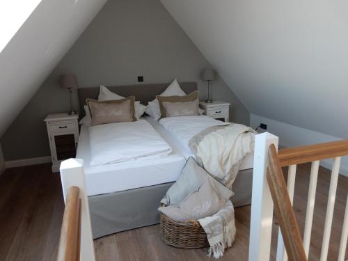 a bed with white sheets and pillows in a attic at Hotel Leegerpark in Greetsiel