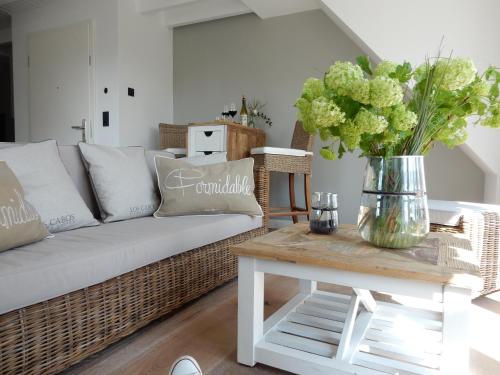 a living room with a couch and a table with flowers at Hotel Leegerpark in Greetsiel