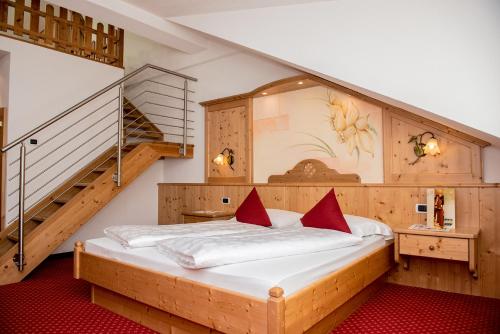 a bedroom with a large bed with a staircase at Loewe Dolomites in San Candido