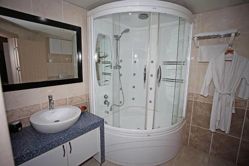 a white bathroom with a shower and a sink at Yildizoglu Hotel in Samsun