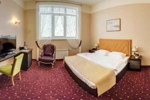 a hotel room with a bed and a desk and a television at Hyde Park Hotel in Tver